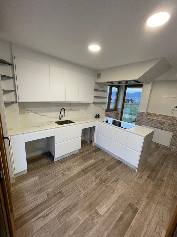 Cocina con península en acabado blanco mate, acompañada de encimera y frontal con veteado tipo mármol Calacatta. Minimalismo y elegancia en cada detalle