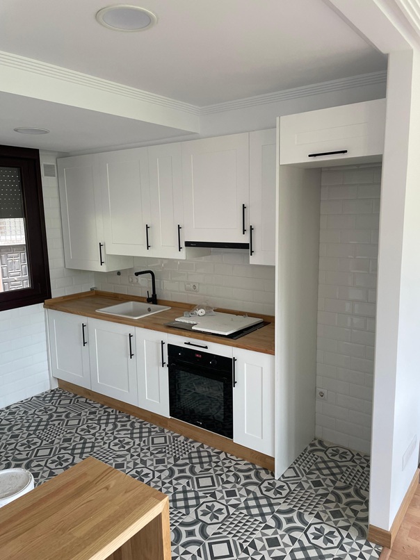 Cocina de inspiración tradicional con frentes blancos enmarcados, encimera de madera y suelo hidráulico. El equilibrio perfecto entre lo clásico y lo moderno
