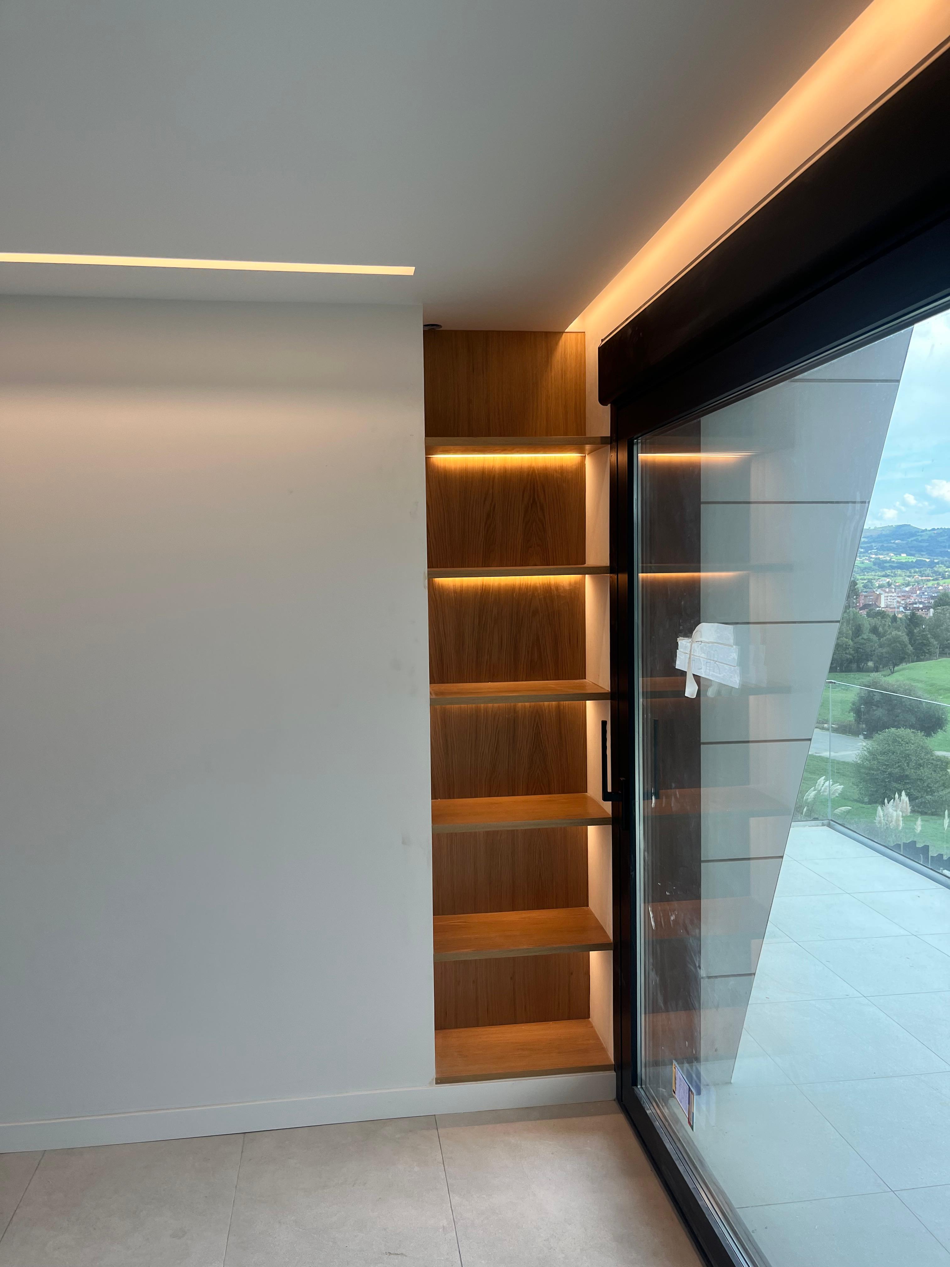 Estantería encastrada a medida en madera de roble con iluminación LED indirecta integrada en cada balda